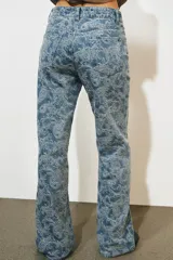 Pantalón jean tiro alto de corte flare con diseño jacquard estampado completo, cinco bolsillos, trabillas para cinto y cierre frontal con cremallera y botón metálico.