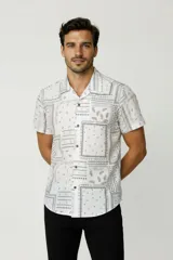 Camisa de manga corta color blanco con estampado tipo bandana en tonos grises, de corte holgado, con cuello camisero y cierre frontal de botones.