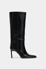 Bota de caña alta y ancha confeccionada en piel, con diseño de punta fina y tacón alto tipo aguja. Presenta costuras decorativas a lo largo del cuerpo y un diseño de calce fácil.