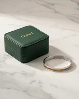 Esclava rígida de acero inoxidable con diseño bicolor, compuesta por una banda plateada lisa y una cadena central con baño de oro.