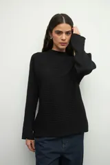 Polera negra de tejido tramado y corte holgado, con mangas acampanadas.