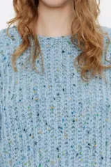 Jersey negro de punto con hilos de colores entretejidos, corte recto, escote barco y mangas largas abullonadas.