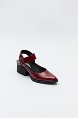 Zapato negro tipo zueco con acabado charol, tira ancha con hebilla metálica y taco ancho de altura media.