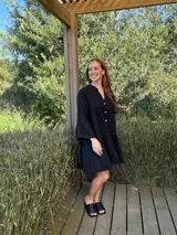 Vestido amplio de lino color verde lima, con cuello mao y abertura frontal con botones de coco. Presenta un diseño con canesú fruncido y volados en los puños de las mangas largas.