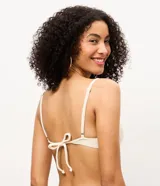 Top de bikini confeccionado en microfibra acanalada, de color beige con aros estructurados y breteles regulables con apliques decorativos ovalados.