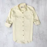 Camisa color amarillo claro, de corte clásico, con cuello mao y mangas largas con puños abotonados.