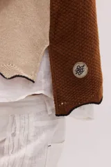 Chaleco de punto de lambswool color mostaza, sin mangas, con cuello redondo y diseño de ochos en la parte delantera.