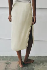 Falda midi de tiro medio color beige en tejido de viscosa con estampado jacquard y aplicación de encaje a tono en el bajo, con cierre lateral de cremallera oculta.
