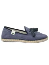 Alpargata de estilo slip-on color azul marino, confeccionada en algodón orgánico. Presenta un detalle de borlas en el empeine y una suela de yute con base de goma antideslizante. Incluye una etiqueta lateral con logo.