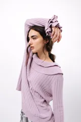 Buzo de tejido acanalado color lila, con cuello redondo decorado con dos volados y mangas largas con tres volados pequeños en los puños.