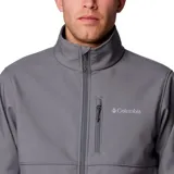 Chaqueta softshell Columbia para hombre, color gris, con cierre frontal, cuello alto, puños y dobladillo ajustables. Presenta bolsillos laterales y un bolsillo en el pecho, todos con cierre.