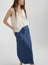 Falda midi de denim azul con diseño de paneles, bolsillos frontales amplios y ruedo deshilachado.