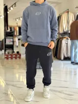 Pantalón jogger negro de corte oversize con felpa, bolsillos laterales y puños elásticos en los tobillos. Presenta un pequeño logo estampado en color blanco en la pierna izquierda.