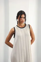 Vestido midi tejido en punto canalé negro con detalles en lurex plateado. Presenta calado artesanal en el ruedo, abertura lateral y etiqueta de cuero en la parte trasera del cuello.