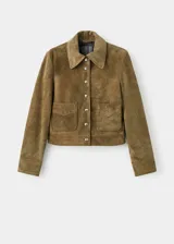 Chaqueta corta de piel de serraje color marrón, con diseño recto, cuello camisero, manga larga y cierre frontal de botones metálicos. Cuenta con dos bolsillos de parche con solapa en la parte delantera y forro interior.