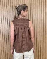 Musculosa de lino color blanco, de corte holgado, con cuello en V, detalles de tablas y frunces en los hombros, y dobladillo desflecado.