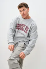 Buzo gris con estampa en el frente con el texto "Brooklyn New York" en color bordó.