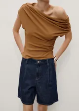 Short de jean azul oscuro, tiro medio, con pinzas delanteras, bolsillos laterales y cierre con cremallera y botón.