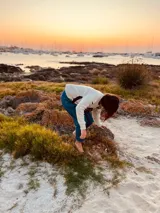 Sweater de lana color crema con cuello redondo, mangas largas y diseño con apliques de cuero negro en forma de V en el frente y bordado de una rosa negra en el pecho.