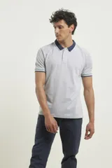 Chomba de piqué azul con cuello clásico, mangas cortas y corte recto. El cuello y los puños tienen detalles a contratono en azul marino y blanco.