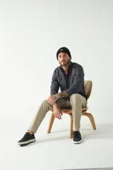 Camisa de hombre color beige con efecto stone wash, corte regular, cuello clásico, cierre frontal con botones, dos bolsillos con solapa abotonada en el pecho y mangas largas con puños abotonados.