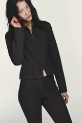 Cazadora entallada de color gris oscuro, con cuello solapa, manga larga y cierre frontal con cremallera de doble cursor. Presenta costuras marcadas y forro interior.