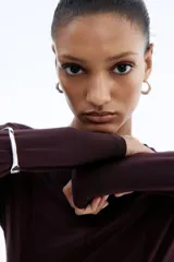 Top de manga larga en punto de crepé, con cuello redondo y diseño con peplum. Presenta costuras moldeadoras en la parte frontal y posterior que definen la silueta.