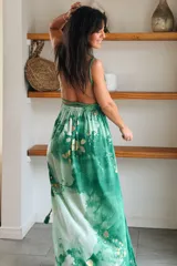 Vestido largo de seda con estampado abstracto en tonos marrones, beige y destellos dorados, con escote en V profundo, tirantes de cuerda anudados al cuello y la cintura, y tajo lateral en la falda.