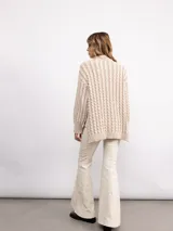 Sweater de punto con diseño de trenzas verticales, cuello alto y silueta oversize. Presenta un patrón bicolor en tonos azul y azul oscuro, con mangas largas y terminaciones en tejido acanalado.