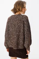 Saco tipo cardigan de tejido de punto con diseño jaspeado en tonos marrón chocolate y crudo. Presenta cuello en V, cierre frontal con botones grandes y mangas largas con hombros caídos.