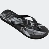 Ojotas Havaianas modelo Aloha con estampado de hojas de palmera en tonos beige, marrón y negro, sobre base blanca. Tiras blancas con textura.