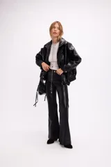 Pantalón de tiro alto confeccionado en cuerina negra, con corte oxford y diseño ajustado en la parte superior que se ensancha hacia el ruedo.