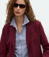 Abrigo largo de corte slim, color gris con textura jaspeada. Presenta solapas clásicas, cierre frontal con botones, bolsillos laterales con solapa y abertura trasera. Incluye forro interno.