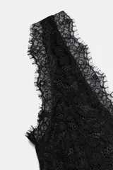 Vestido midi negro confeccionado en encaje de algodón, con escote en pico, diseño sin mangas, forro interior y bajo asimétrico.