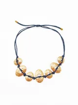 Collar con cordón azul y dijes dorados con textura irregular.