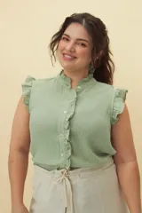 Camisa color amarillo pálido con textura arrugada, cuello mao con volados, cierre frontal con botones y mangas cortas con volados.