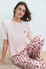 Pijama compuesto por una remera de manga corta en color rosa claro con un pequeño bordado de labios en el pecho y un pantalón largo estampado con motivos de labios en tonos rojos y rosas.