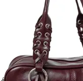 Bolso tipo barrel o doctor bag de cuero charol color vino tinto. Presenta dos asas superiores con detalle de trenzado y ojales metálicos, y múltiples tiras largas de cuero colgando de los herrajes circulares frontales. Incluye correa ajustable para llevar al hombro.