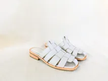 Sandalias bajas de cuero sintético color gris claro, con diseño de tiras entretejidas y suela plana.