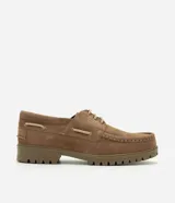 Zapato estilo náutico para hombre, confeccionado en cuero gamuza color marrón. Presenta diseño liso con puntera redondeada, costura aparente en la capellada, cordones bicolor y suela tractorada engomada.