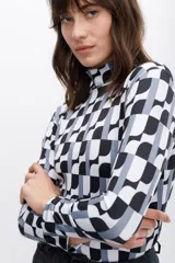 Polera de cuello alto con estampado geométrico en blanco, negro y gris.