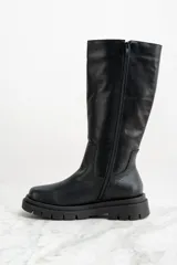 Bota de caña media color negro, confeccionada en cuero, con suela track y puntera redondeada.