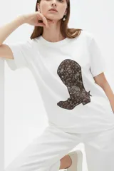 Remera blanca de manga corta y cuello redondo, confeccionada en algodón, con un diseño holgado y estampado frontal de estrella roja con textura y detalles de estrellas pequeñas.