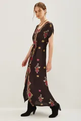 Vestido largo de viscosa en color negro con estampado étnico multicolor, escote en V profundo, mangas cortas y ajuste en la cintura con cordón. Presenta una abertura frontal central.