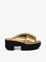 Sandalias doradas con plataforma negra y base amarilla. Tiras anchas y acolchadas de piel de oveja.