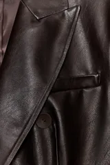 Blazer de corte cruzado confeccionada en material efecto piel, con cuello solapa, manga larga con hombreras, bolsillos delanteros con solapa y cierre frontal con botones.