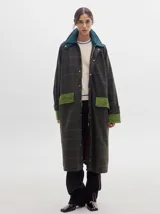 Trench oversize de lana a cuadros con cuello, puños y bolsillos de pana verde.