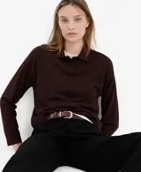 Jersey de punto color bordó, con cuello polo y cierre frontal de botones cortos, de manga larga y diseño recto.