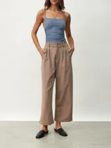 Pantalón de vestir color tostado de corte ancho y relajado, tiro alto con trabillas para cinturón, pinzas frontales y bolsillos laterales.