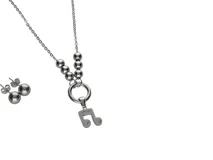 Set de acero plateado. Incluye collar con cadena de eslabones, dije de nota musical y caravanas en forma de esfera.